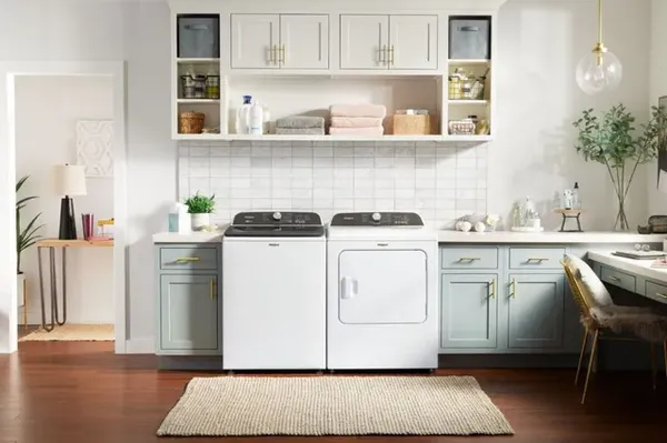 The Whirlpool WTW6157PW top load washer and matching dryer in a laundry room